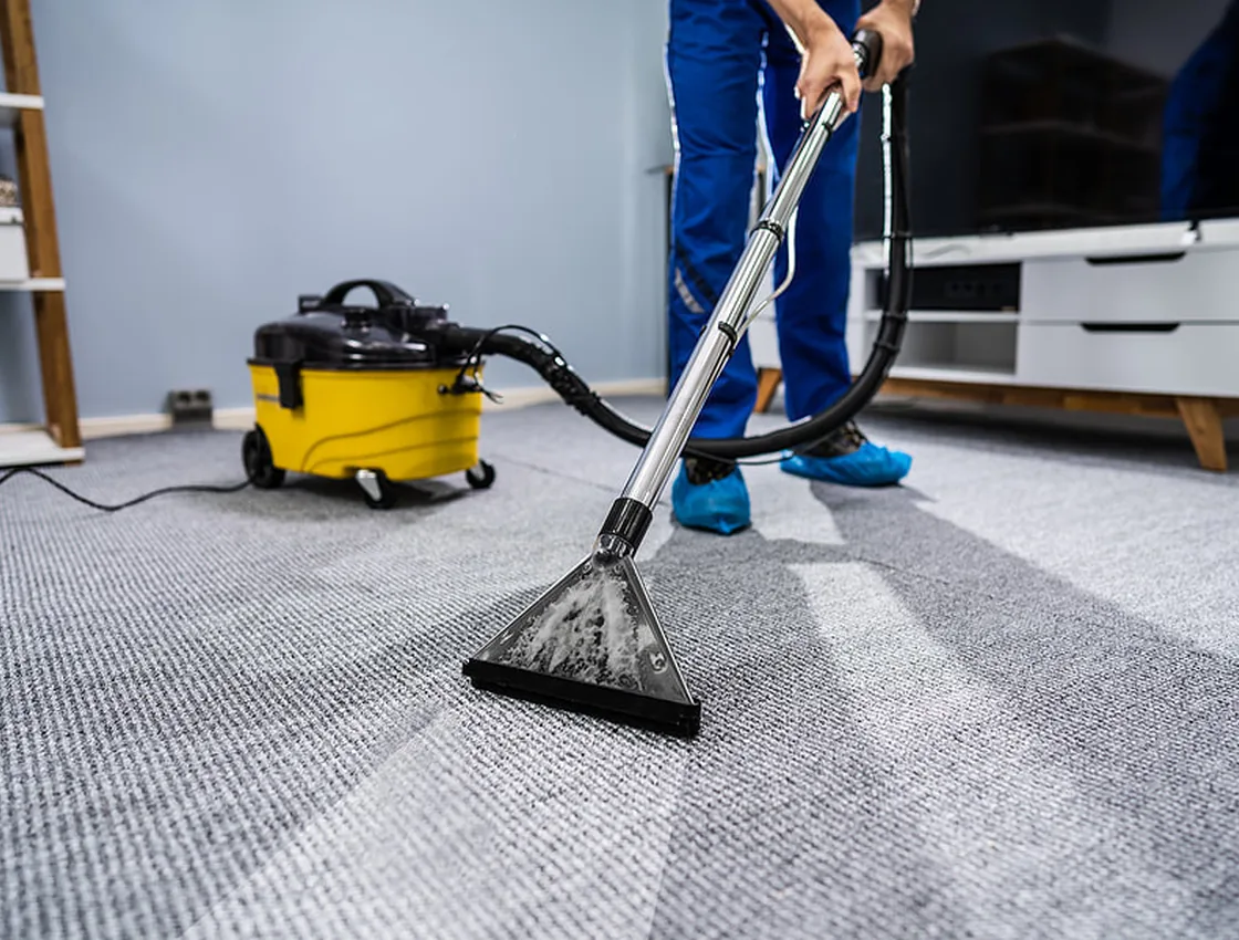 A technician running a carpet extraction wand across commercial carpet, leaving a visibly cleaner stripe behind.